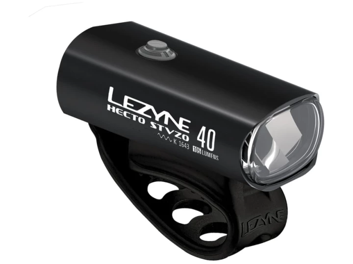 Ein schwarz-weißes Lezyne Hecto Drive 40 StVZO-Fahrradlicht mit kompaktem, robustem Design. Es ist in unserem Online-Fahrradshop erhältlich und verfügt über eine klare Linse und einen großen Knopf oben. Es ist an einem Silikonband befestigt, sodass Sie es ganz einfach an Ihrem Fahrrad befestigen können. Der Produkt- und Markenname sind auf der Seite des Lichts aufgedruckt.