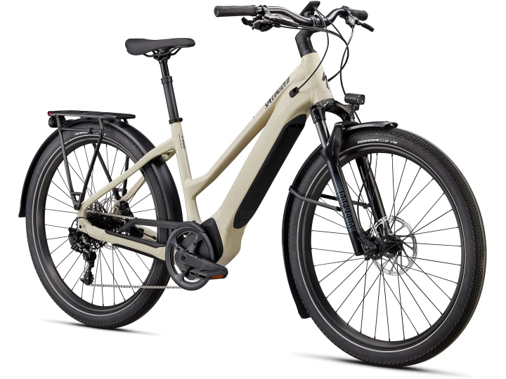 Das Specialized Turbo Vado 5.0 ST hat einen beigen Rahmen, schwarze Reifen und eine Vorderradgabel mit Federung. Es verfügt über Scheibenbremsen, einen Gepäckträger und einen integrierten Akku entlang des Unterrohrs. Das Fahrrad wird aus einem 3/4-Winkel gezeigt, wodurch der Antriebsstrang und der Lenker hervorgehoben werden. Jetzt in Ihrem Lieblingsfahrradladen erhältlich.