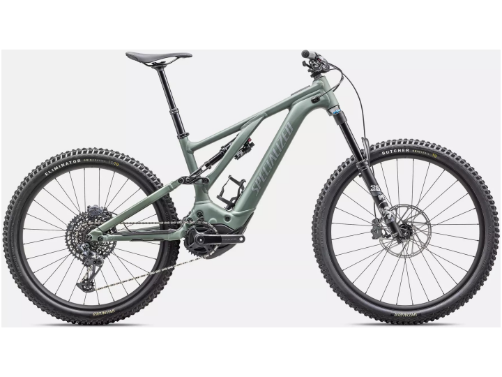 Das Specialized Turbo Levo Comp Alloy ist ein modernes, mattgrünes Mountainbike mit dicken Offroad-Reifen und einem robusten Rahmen. Mit Doppelfederung, breitem Lenker und fortschrittlichen Getriebekomponenten ist dieses Fahrrad perfekt für unwegsames Gelände geeignet. Es steht vor einem schlichten weißen Hintergrund.