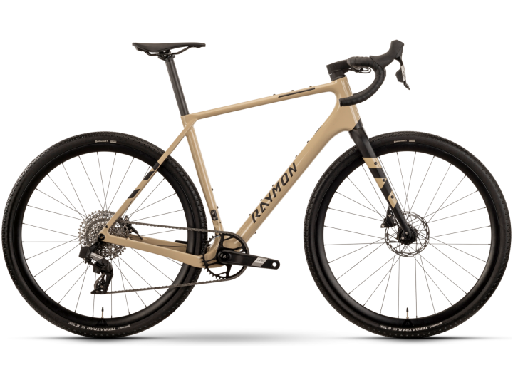 Das Raymon Soreno Pro ist ein elegantes Fahrrad mit beige-schwarzem Rahmen, Rennlenker, Scheibenbremsen und dem „RAYMON“-Logo. Es besticht durch sein modernes Design mit robusten Reifen für gemischtes Gelände vor einem schlichten weißen Hintergrund.