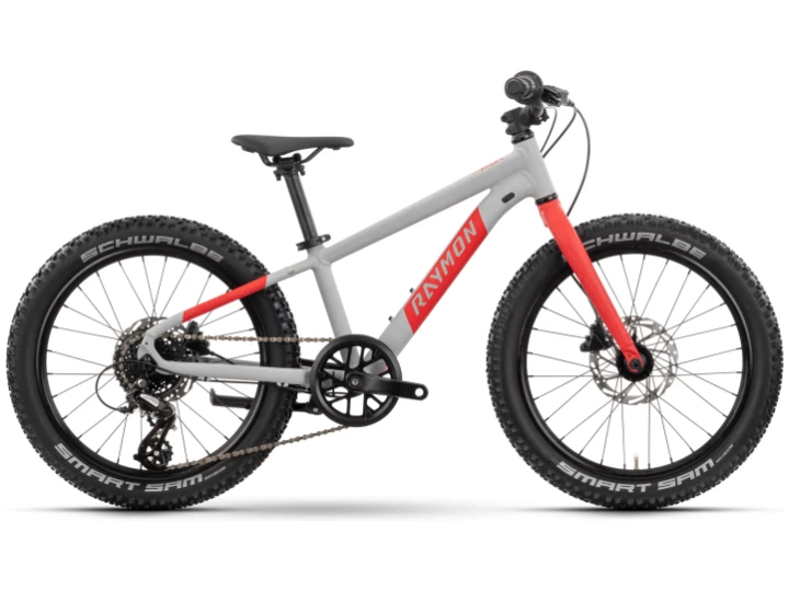 Das Raymon Yanga 20 Pro ist ein Kinder-Mountainbike mit weißem und rotem Rahmen, schwarzem Sattel, dicken Schwalbe-Reifen, Scheibenbremsen und Gangschaltung, von der Seite vor weißem Hintergrund.