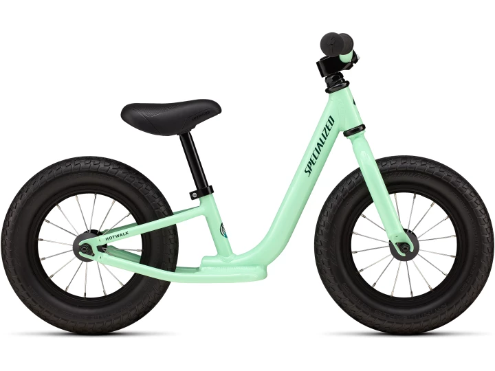 Das Specialized Hotwalk ist ein hellgrünes Balance-Bike ohne Pedale, mit schwarzem Lenker, Sitz und Reifen und dem Schriftzug "Specialized" auf dem Rahmen.