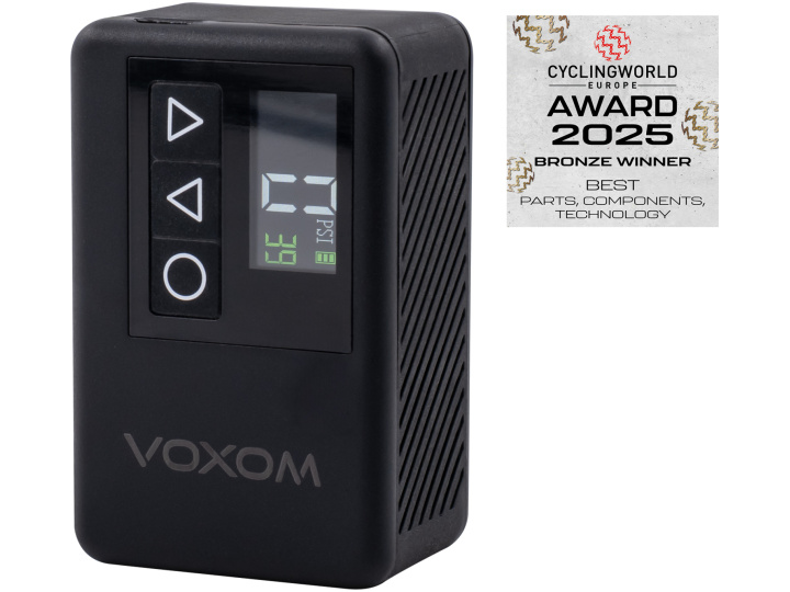 Eine kompakte schwarze Voxom elektrische Pumpe EPu2 mit einem Display, das "23 PSI" anzeigt, und Bedientasten, neben einer "Cyclingworld Europe Award 2025 Bronze Winner"-Plakette für die besten Teile, Komponenten und Technologien.