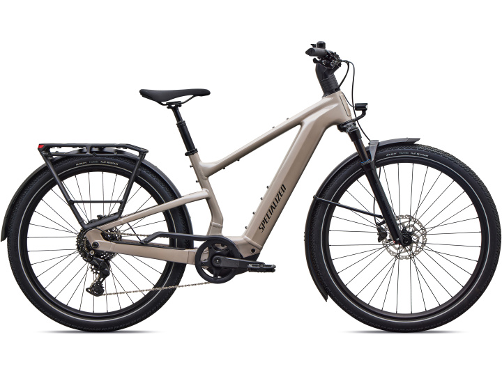 Das Specialized Turbo Vado 3 4.0, ein E-Bike in Beige mit schwarzen Reifen, Scheibenbremsen, Gepäckträger und Schutzblechen, ist im Seitenprofil vor einem weißen Hintergrund abgebildet.
