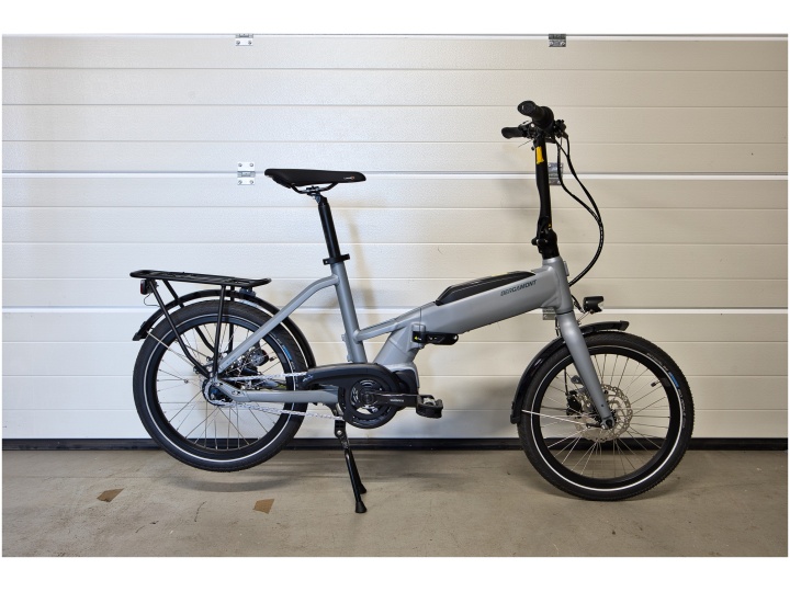 Ein silbernes Klapp-E-Bike der Marke „Bergamont Paul-E EQ Edition“ mit Gepäckträger und Ständer steht im Innenbereich vor einem weißen Garagentor.